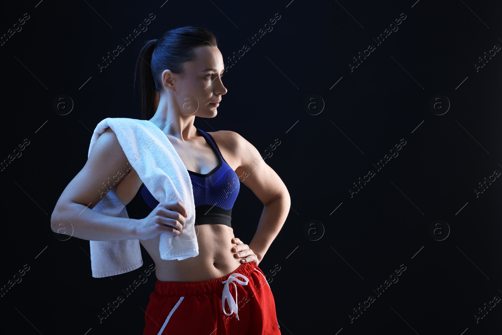 Photo of Sporty woman with terry towel on dark background. Space for text