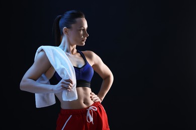 Photo of Sporty woman with terry towel on dark background. Space for text