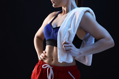 Photo of Sporty woman with terry towel on dark background, closeup