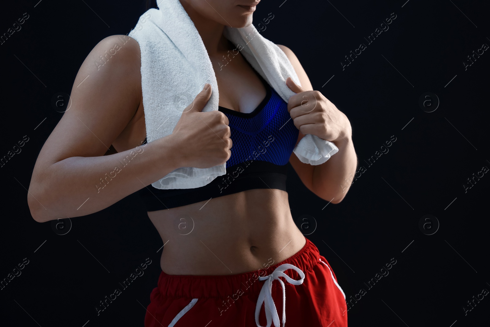 Photo of Sporty woman with terry towel on dark background, closeup