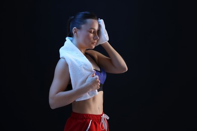 Photo of Sporty woman with terry towel on dark background. Space for text