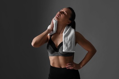 Photo of Sporty woman with terry towel on dark grey background