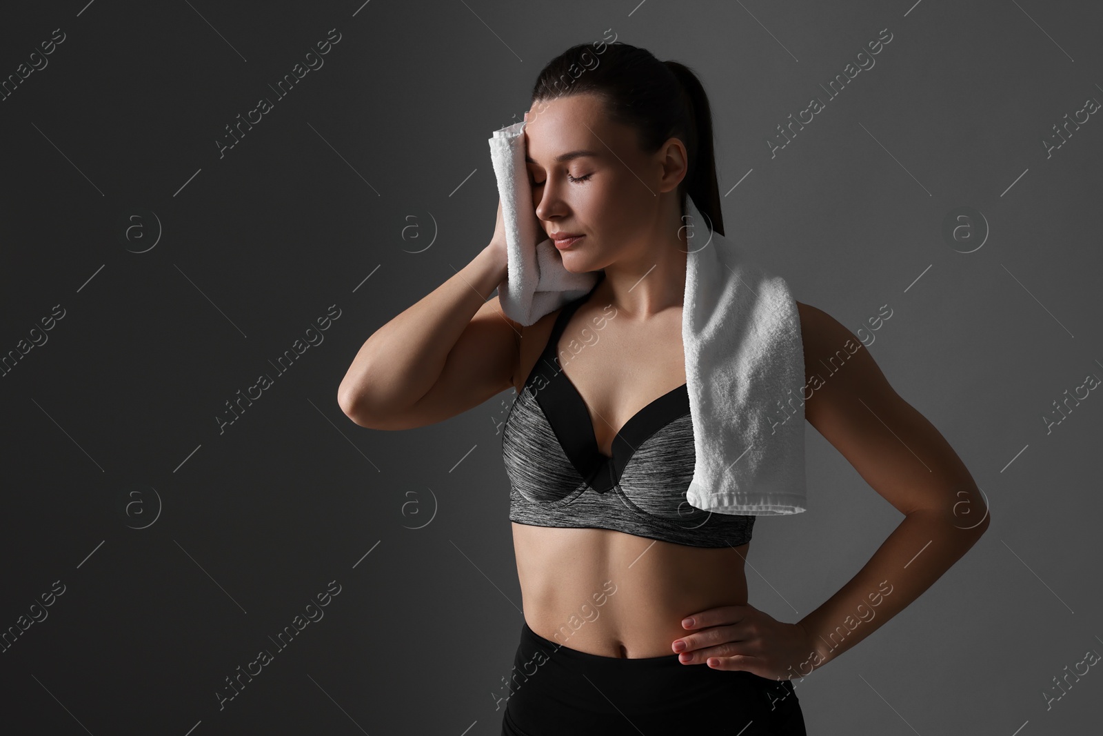 Photo of Sporty woman with terry towel on dark grey background. Space for text