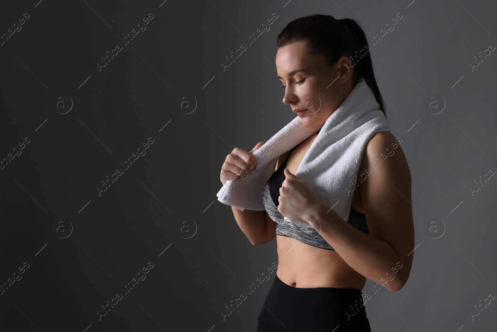 Photo of Sporty woman with terry towel on dark grey background. Space for text