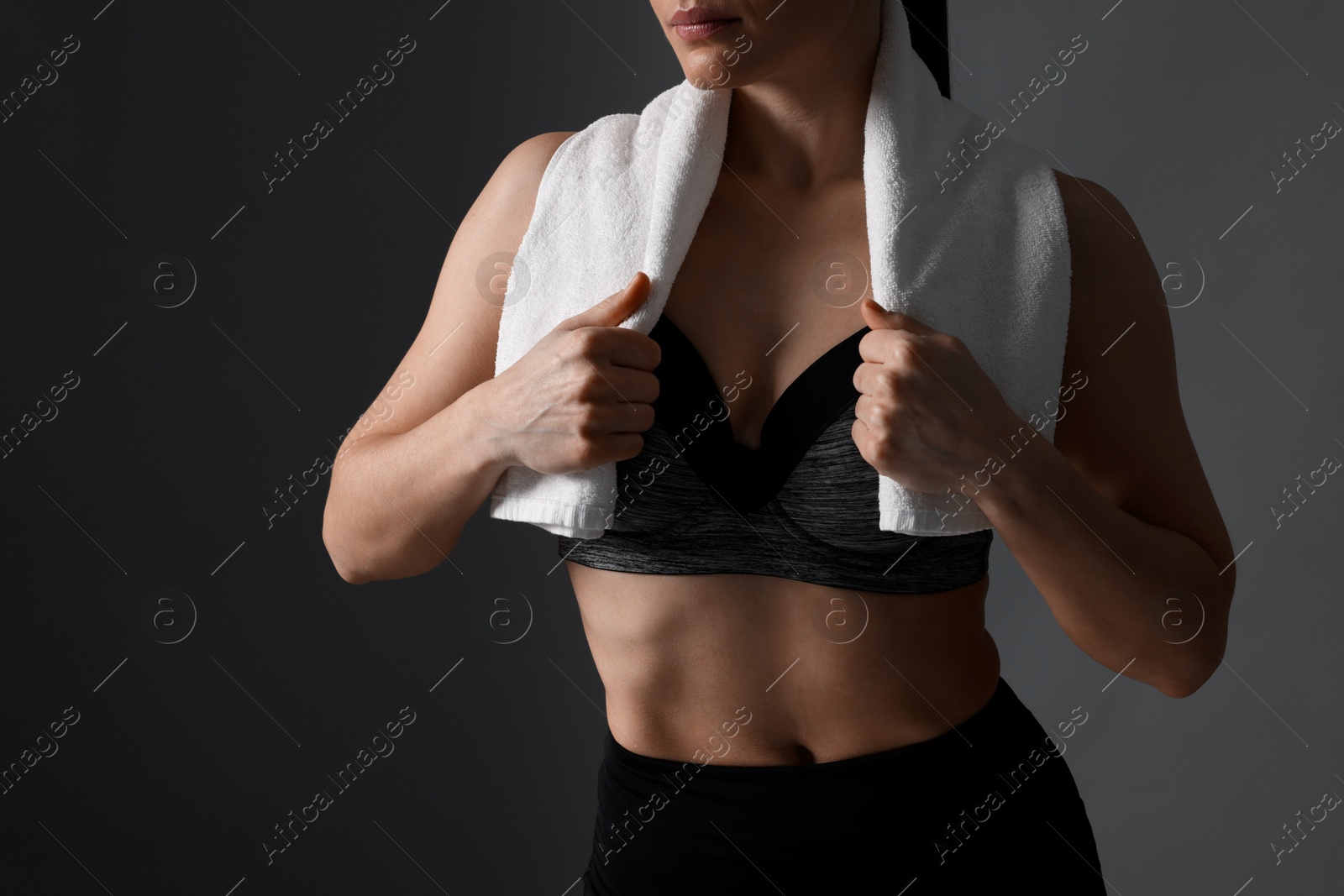 Photo of Sporty woman with terry towel on dark grey background, closeup