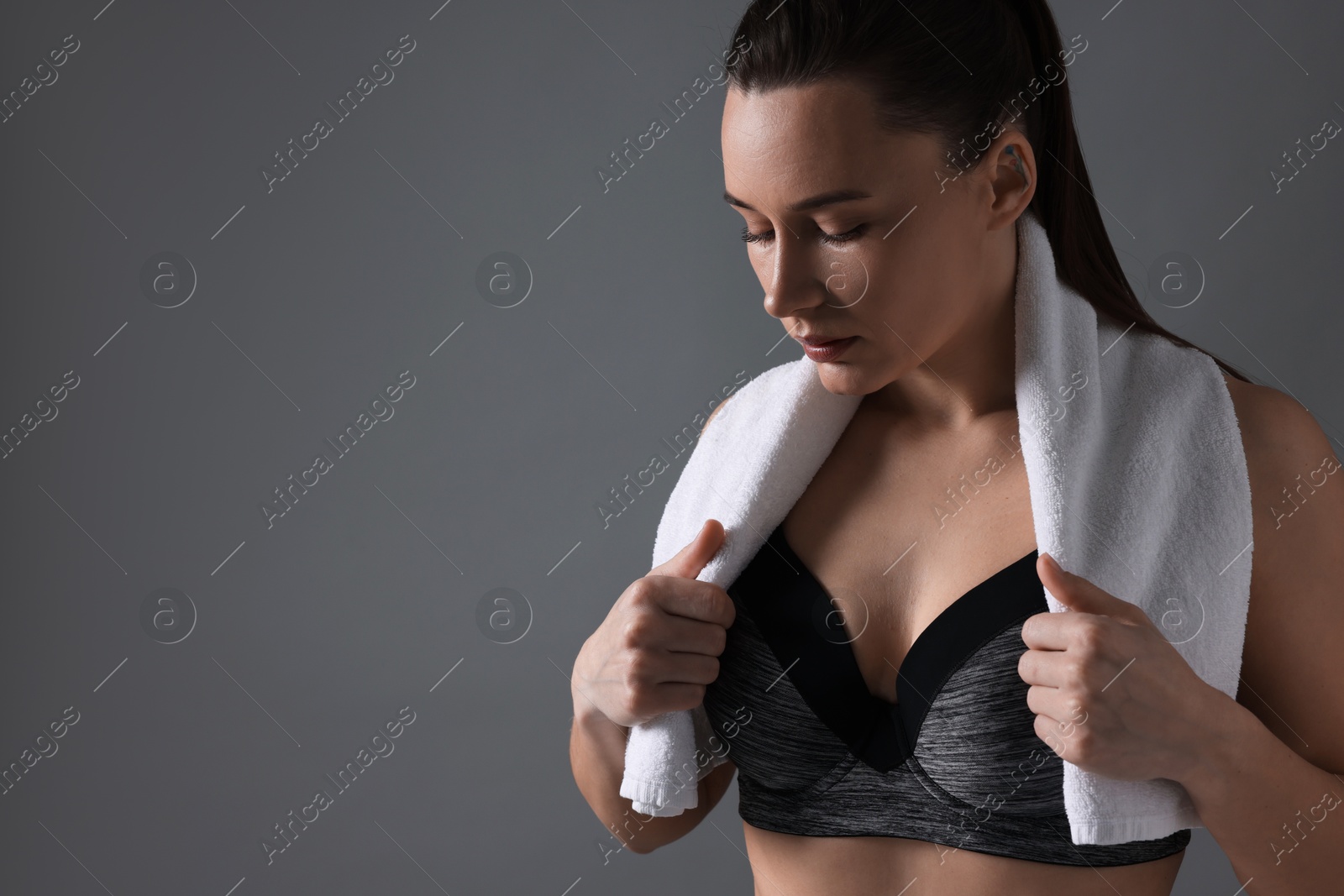 Photo of Sporty woman with terry towel on grey background, space for text