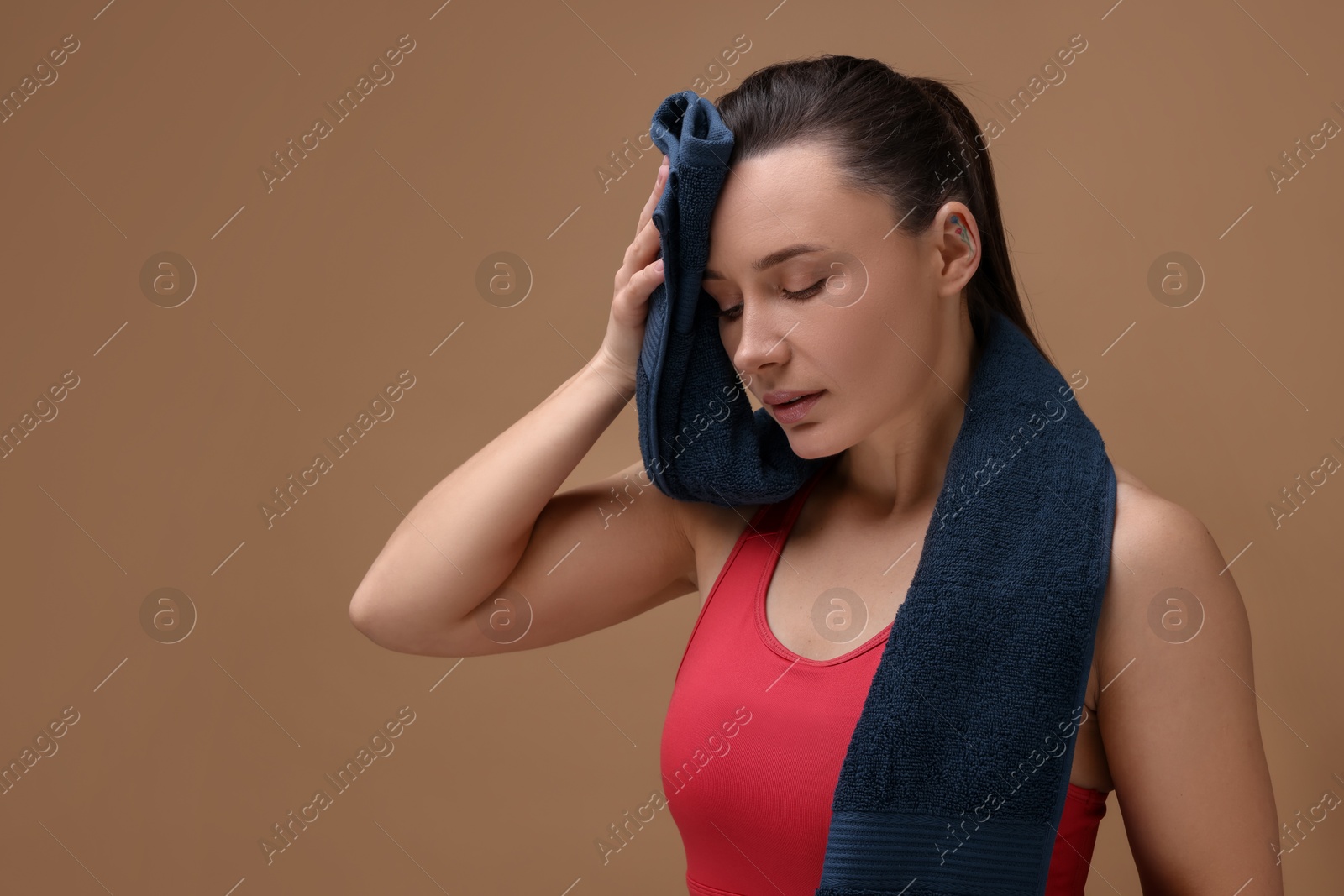 Photo of Sporty woman with terry towel on brown background, space for text