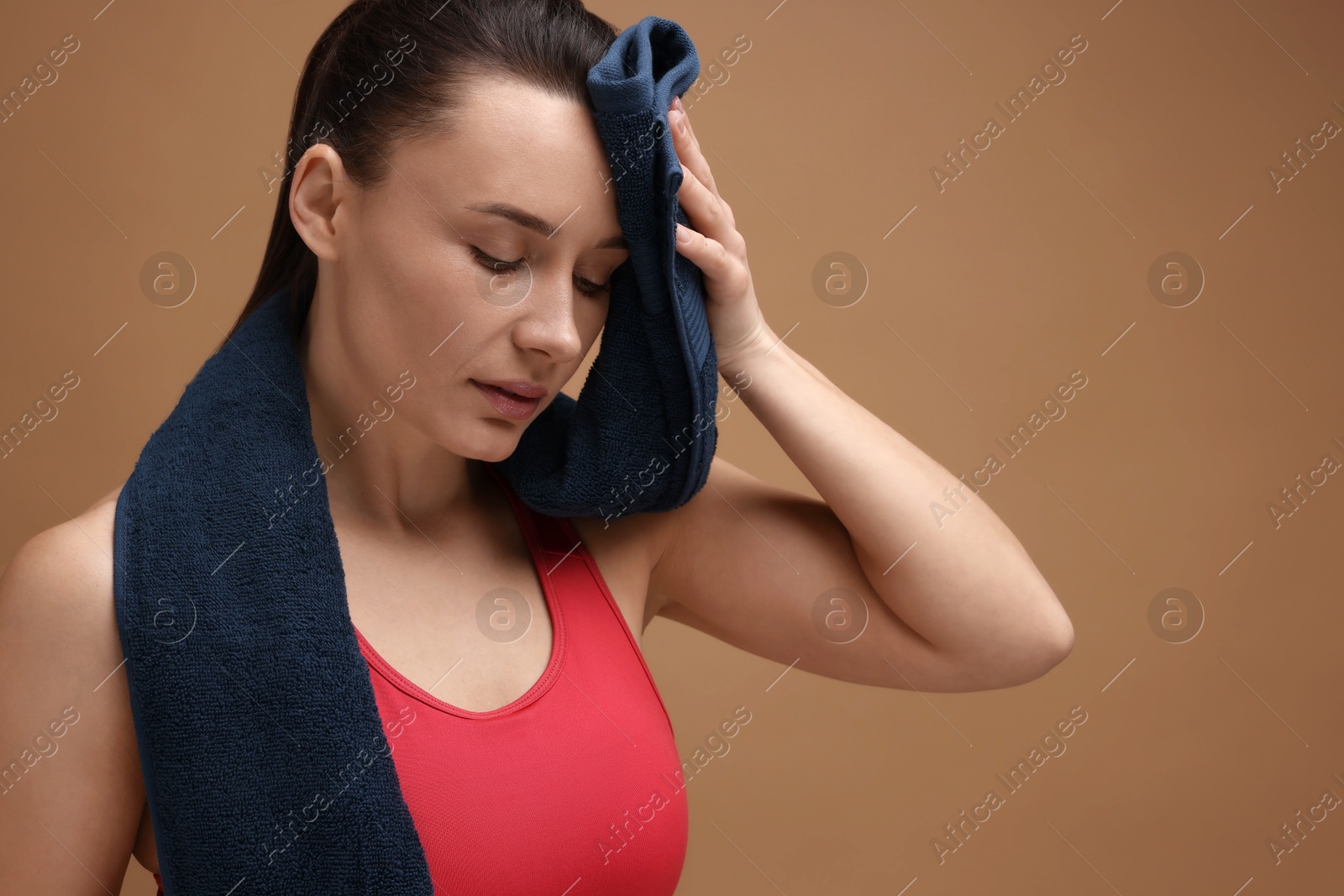 Photo of Sporty woman with terry towel on brown background, space for text