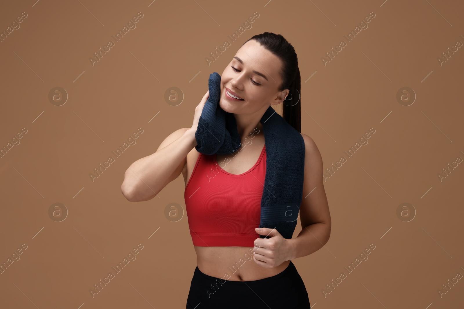 Photo of Sporty woman with terry towel on brown background