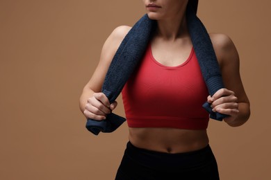 Photo of Sporty woman with terry towel on brown background, closeup. Space for text