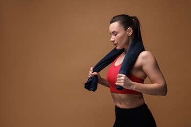 Photo of Sporty woman with terry towel on brown background. Space for text