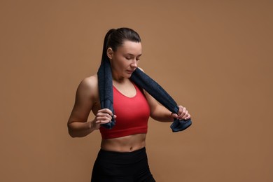 Photo of Sporty woman with terry towel on brown background