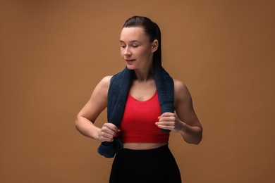 Photo of Sporty woman with terry towel on brown background