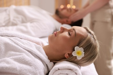 Photo of Couple receiving relaxing massage in spa salon, selective focus