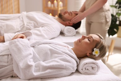 Photo of Couple receiving relaxing massage in spa salon, selective focus