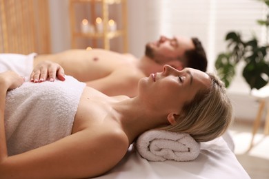 Photo of Couple lying on massage tables in spa salon, selective focus