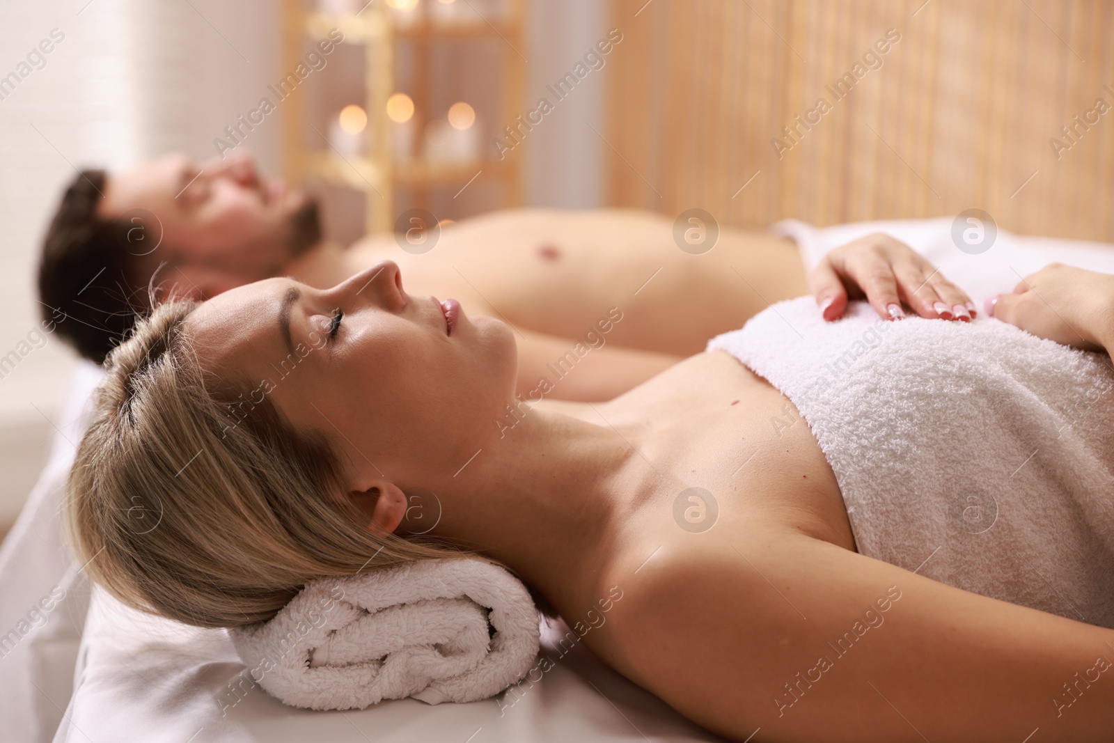 Photo of Couple lying on massage tables in spa salon, selective focus