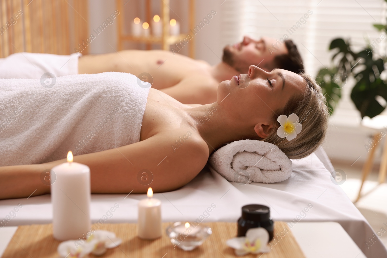 Photo of Couple lying on massage tables in spa salon, selective focus