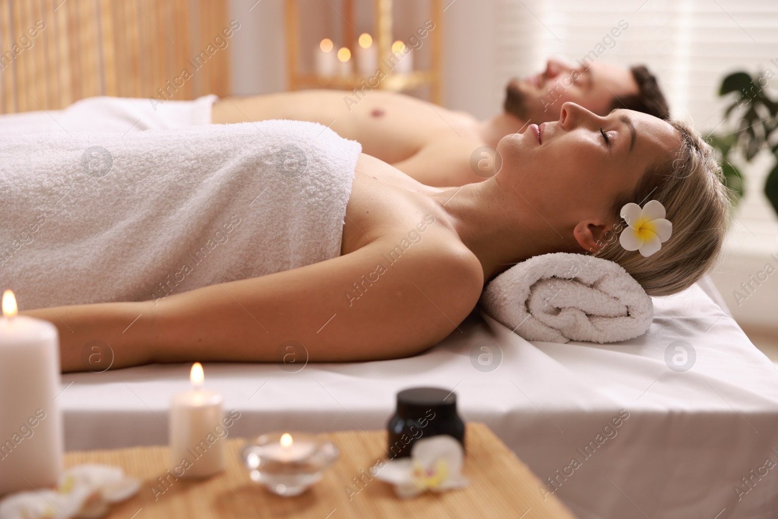 Photo of Couple lying on massage tables in spa salon, selective focus