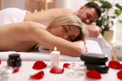 Photo of Couple lying on massage tables in spa salon, selective focus