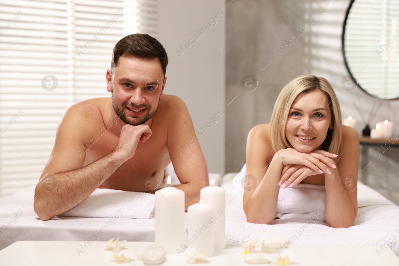 Photo of Happy couple lying on massage tables in spa salon