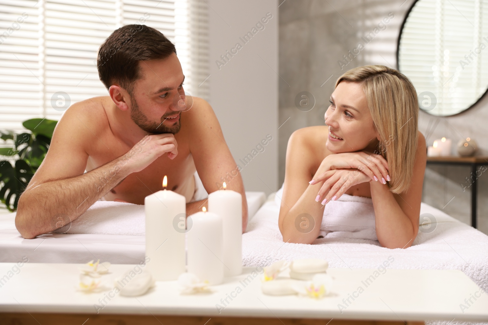 Photo of Happy couple lying on massage tables in spa salon