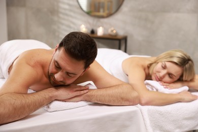 Photo of Couple lying on massage tables in spa salon, selective focus