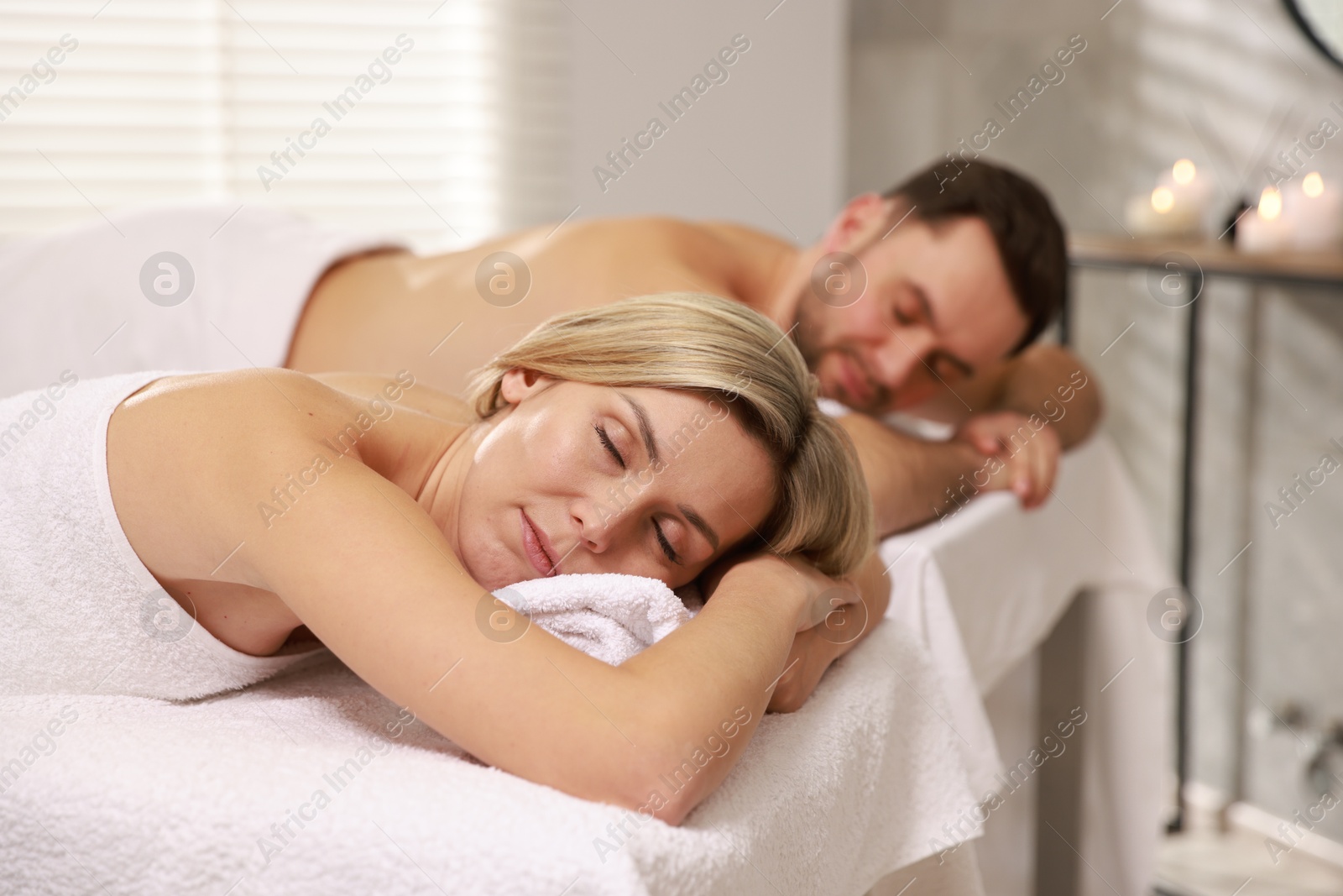 Photo of Couple lying on massage tables in spa salon, selective focus