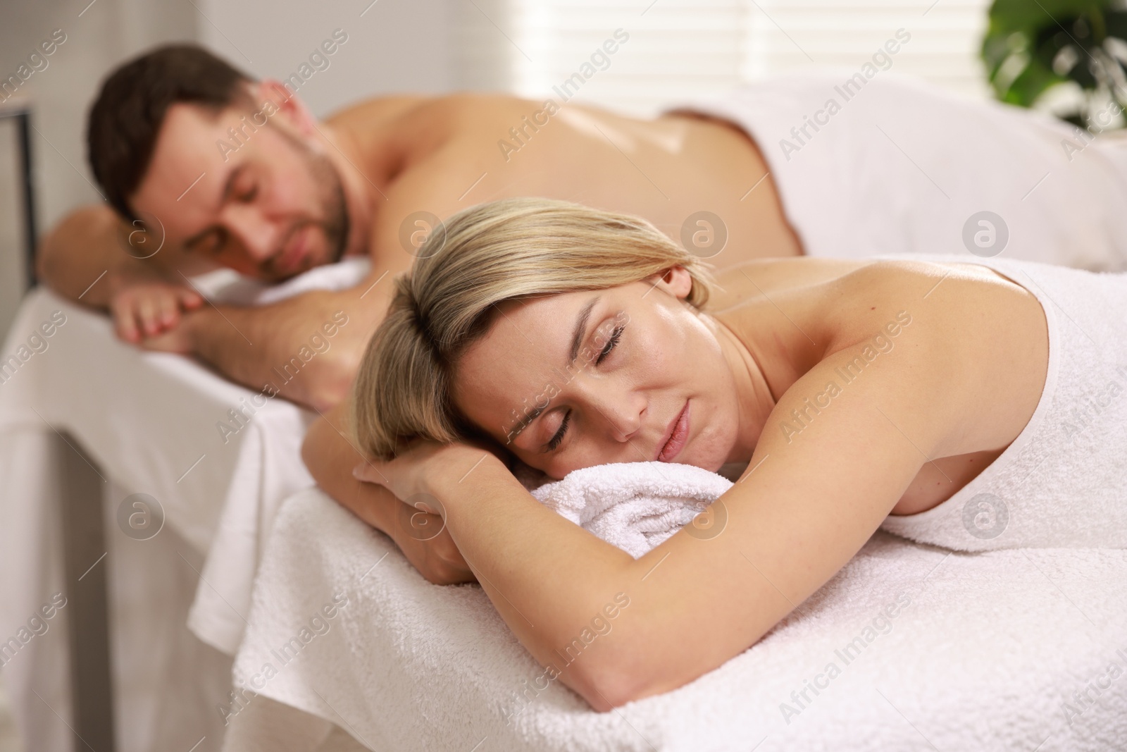 Photo of Couple lying on massage tables in spa salon, selective focus