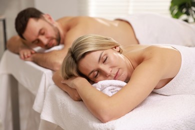 Photo of Couple lying on massage tables in spa salon, selective focus