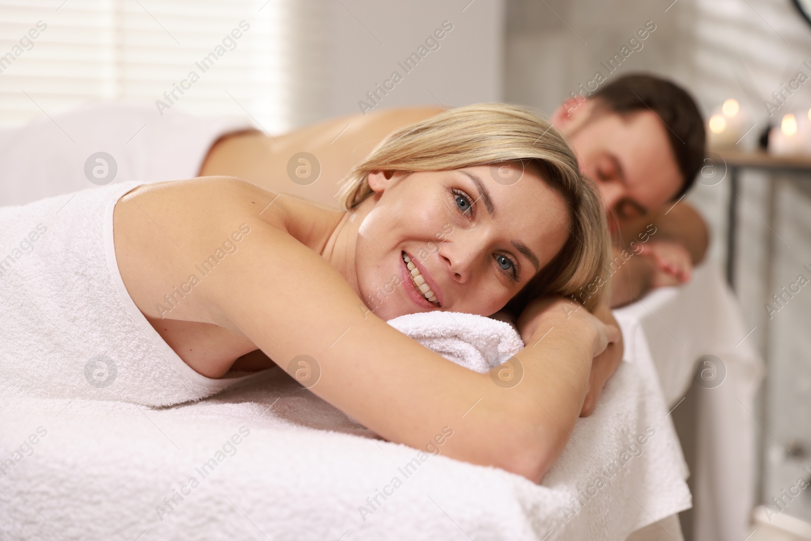 Photo of Happy couple lying on massage tables in spa salon, selective focus