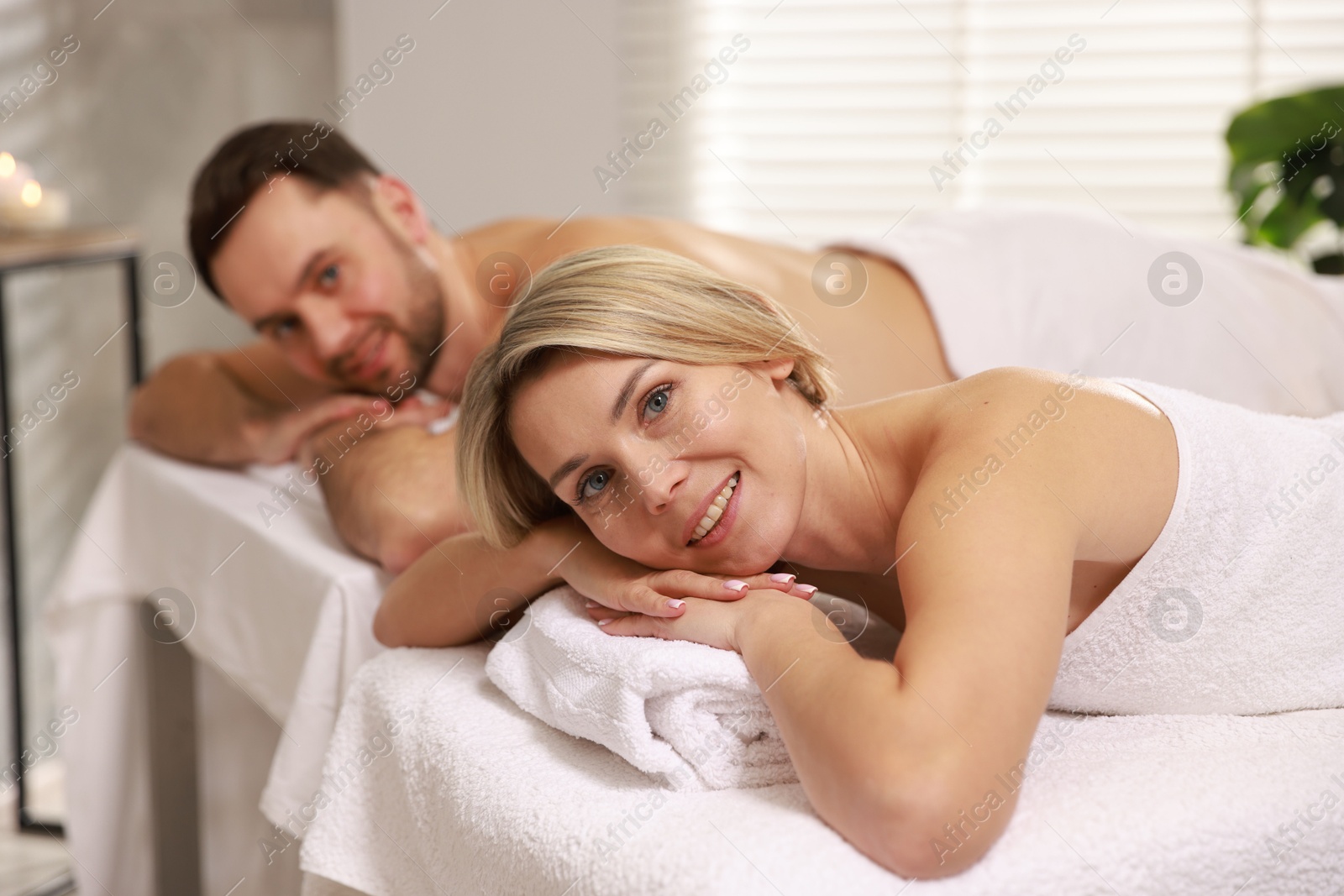 Photo of Happy couple lying on massage tables in spa salon, selective focus