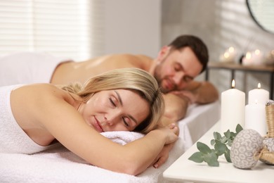 Photo of Couple lying on massage tables in spa salon, selective focus