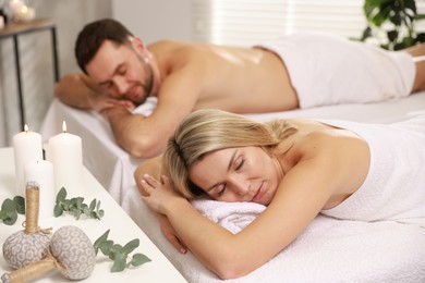 Photo of Couple lying on massage tables in spa salon, selective focus