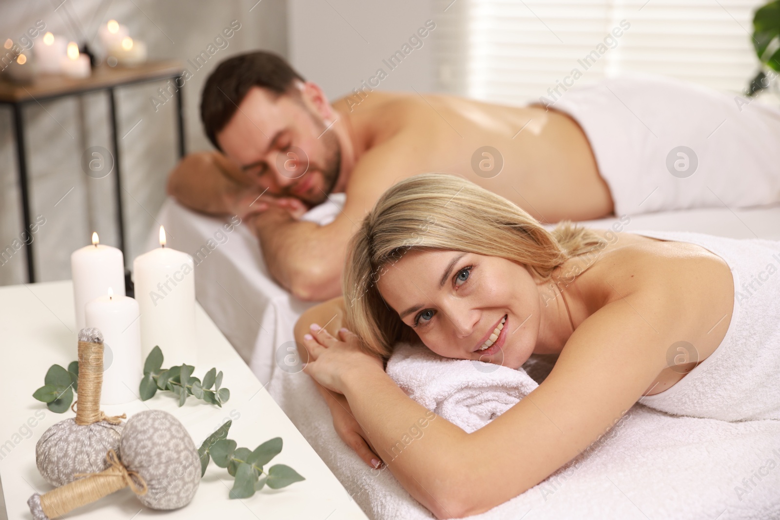 Photo of Happy couple lying on massage tables in spa salon, selective focus