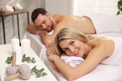 Photo of Happy couple lying on massage tables in spa salon, selective focus