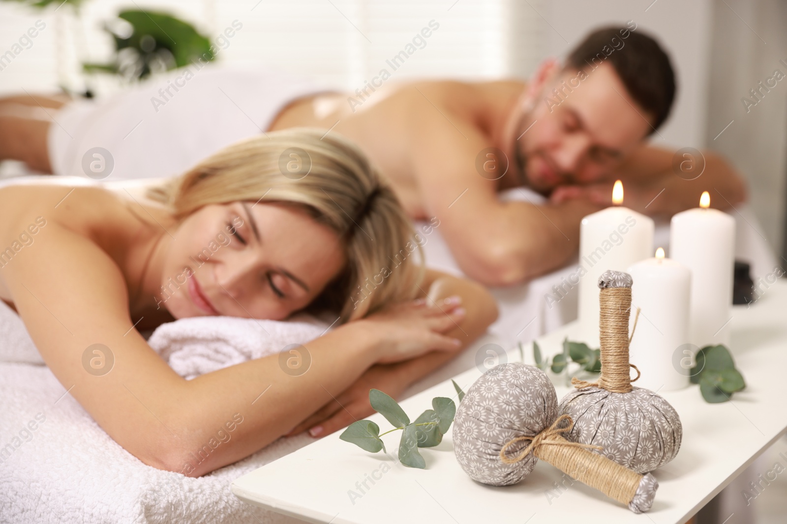 Photo of Couple lying on massage tables in spa salon, selective focus