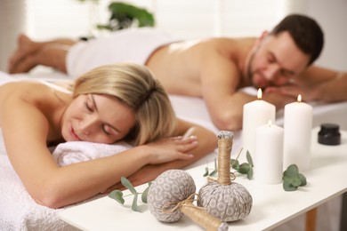 Photo of Couple lying on massage tables in spa salon, selective focus