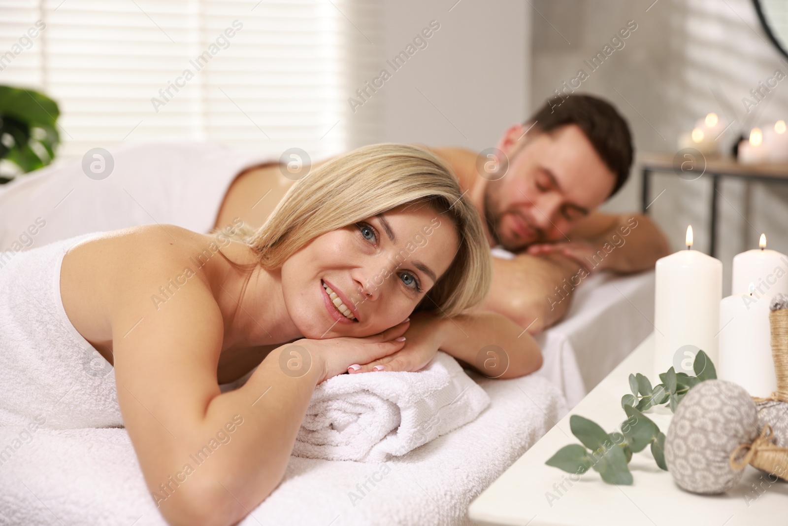 Photo of Happy couple lying on massage tables in spa salon, selective focus