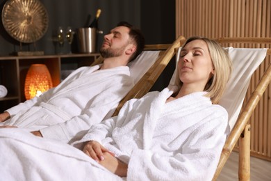 Photo of Couple in bathrobes relaxing in spa salon, selective focus