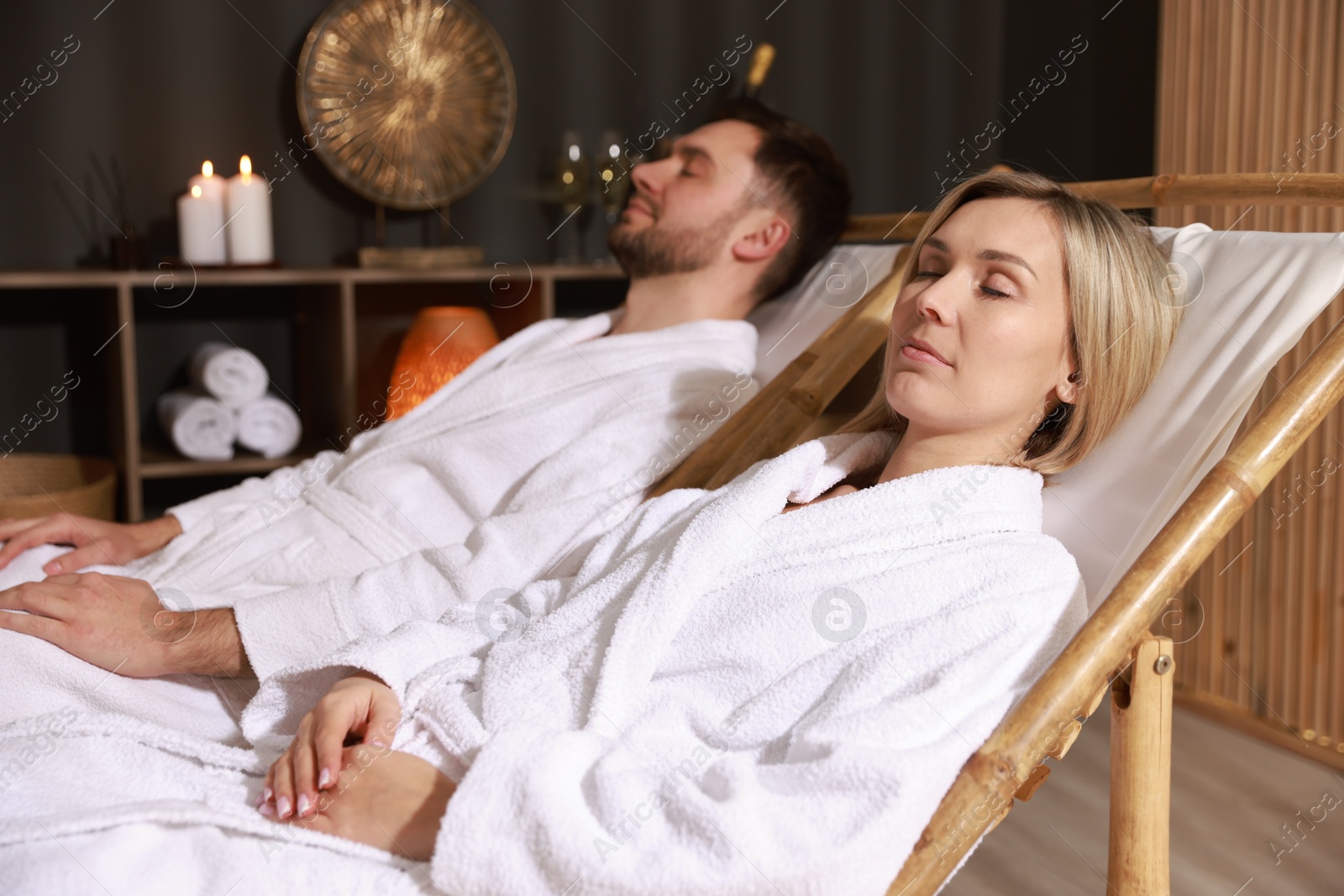 Photo of Couple in bathrobes relaxing in spa salon, selective focus