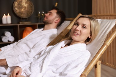 Photo of Happy couple in bathrobes relaxing in spa salon, selective focus