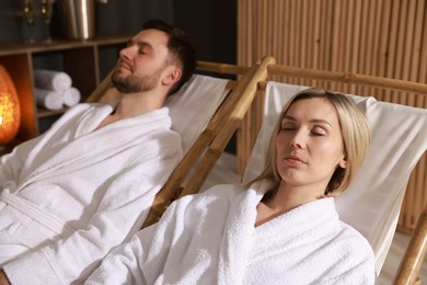 Photo of Couple in bathrobes relaxing in spa salon, selective focus