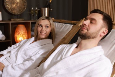 Photo of Happy couple in bathrobes relaxing in spa salon