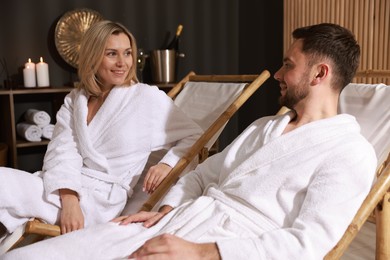 Photo of Happy couple in bathrobes relaxing in spa salon