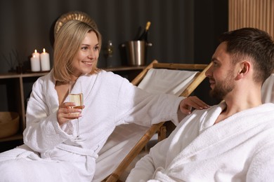 Photo of Happy couple in bathrobes relaxing in spa salon