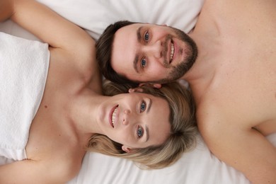 Photo of Spa. Happy couple lying on bed, top view