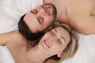 Photo of Spa. Happy couple lying on bed, above view