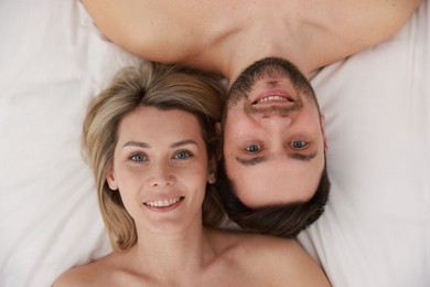 Photo of Spa. Happy couple lying on bed, top view