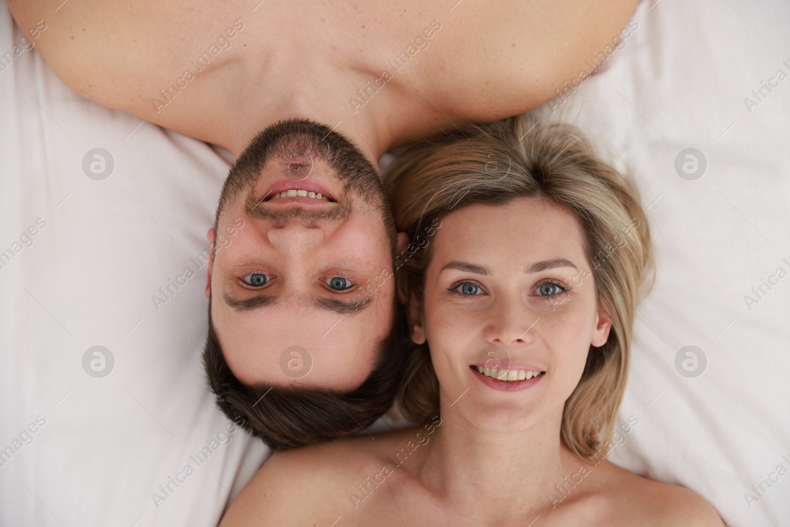 Photo of Spa. Happy couple lying on bed, top view